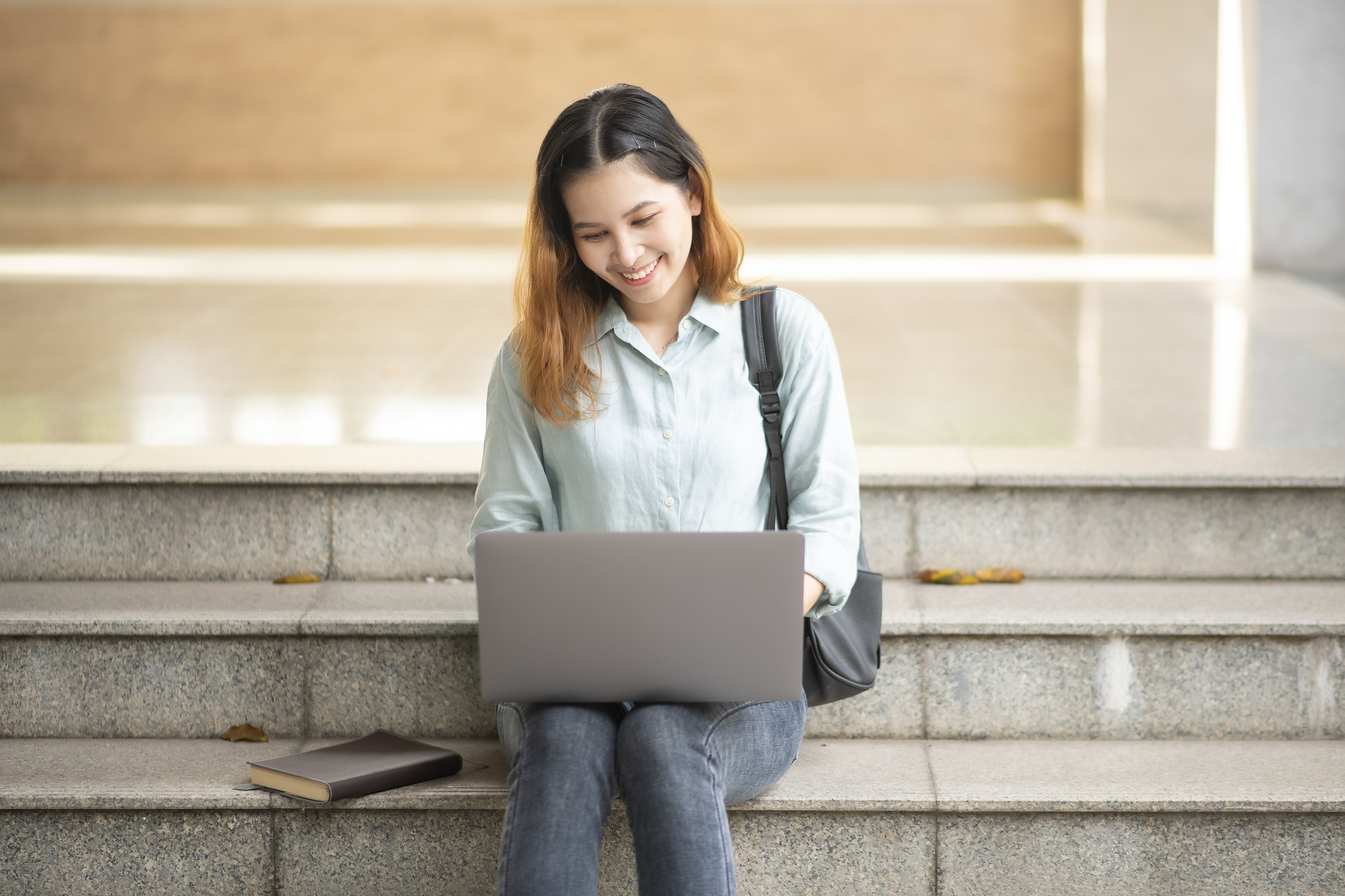 Studentka SGH z laptopem na kolanach siedząca na schodach
